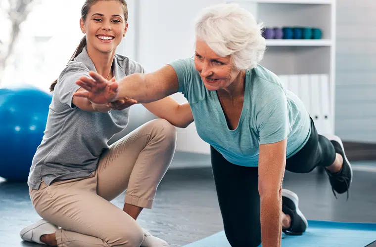 Kinesitherapeute aidant une femme agee a faire des exercices d etirement - arthorse | Dr Jerome Auger Paris 16
