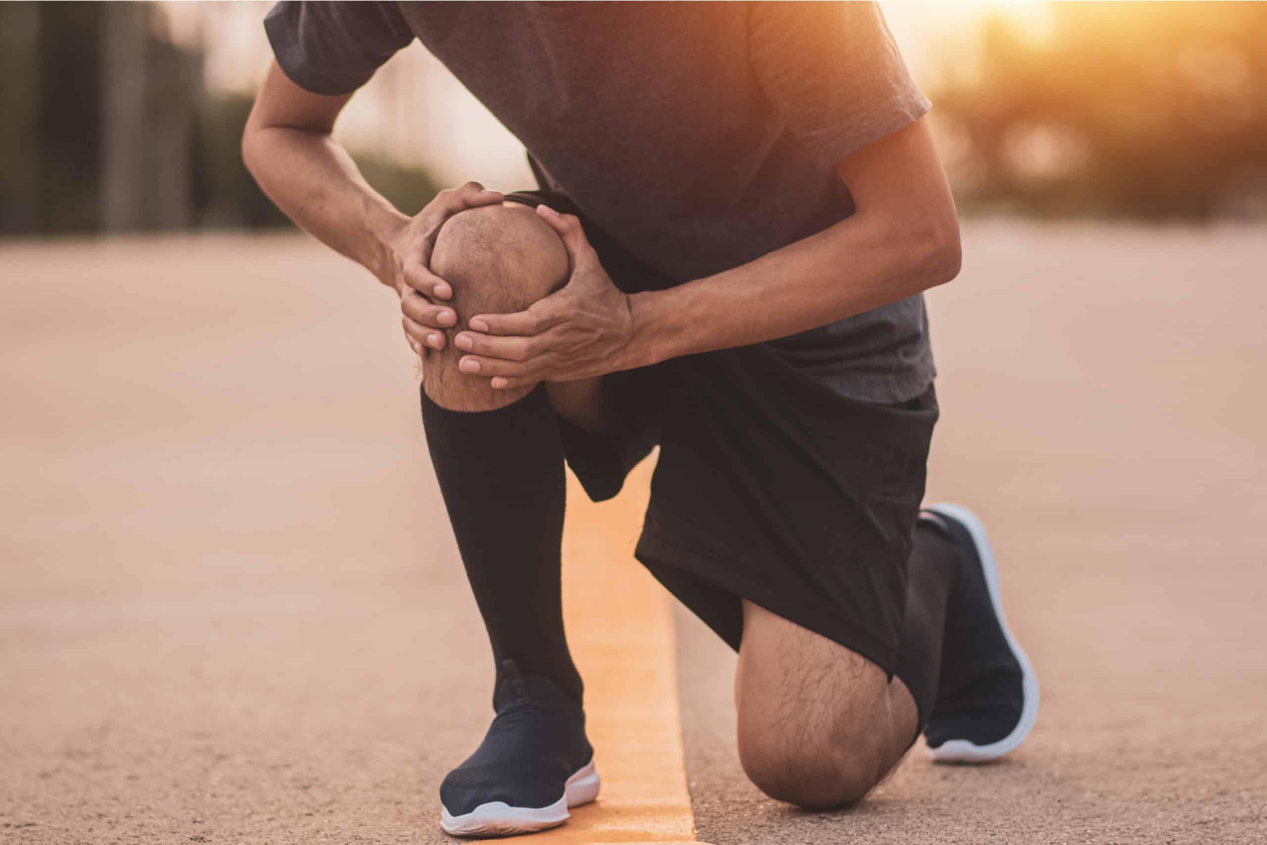 Jeune homme faisant du sport tenant son genou qui lui fait mal - comment reprendre la course a pieds | Dr Jerome Auger Paris 16